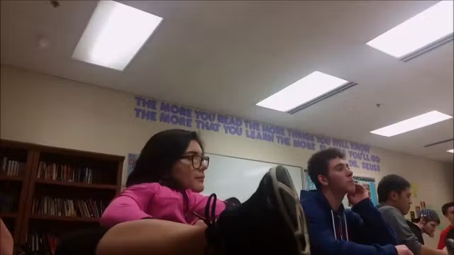 Geeky girl sits with legs on school desk